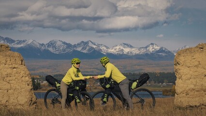 The man and woman travel on mixed terrain cycle bike touring with bikepacking. The two people...