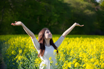 Naklejka na ściany i meble relaxed young girl in a yellow rape field