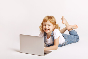 A girl on a white background lies with a laptop.