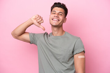 Young caucasian man wearing band-aids isolated on pink background proud and self-satisfied