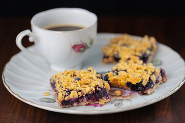blueberry crumb bars on antique plate with cup of coffee. 