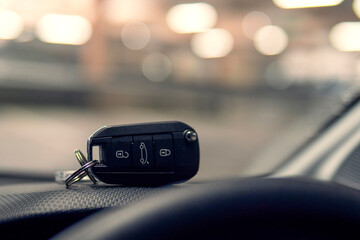 Remote car key on dash board in focus. Car park out of focus in the background. Transportation...