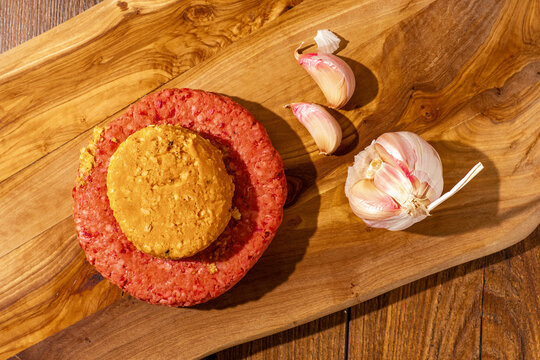 Premium Beef Burger With Cheese And Garlic Melt On A Wooden Board And Table. Butcher Craft, Meat Industry Product. High Quality Hamburger. Top Down View