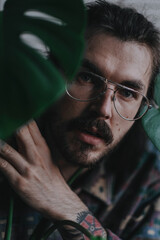 Man looking to camera through the leaf of a plant