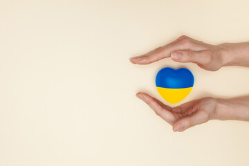 Heart with print the national flag of ukraine in female hand. Flat lay. Copy space.