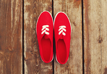 Summer image of pink gumshoes on a wooden table or floor background, top view