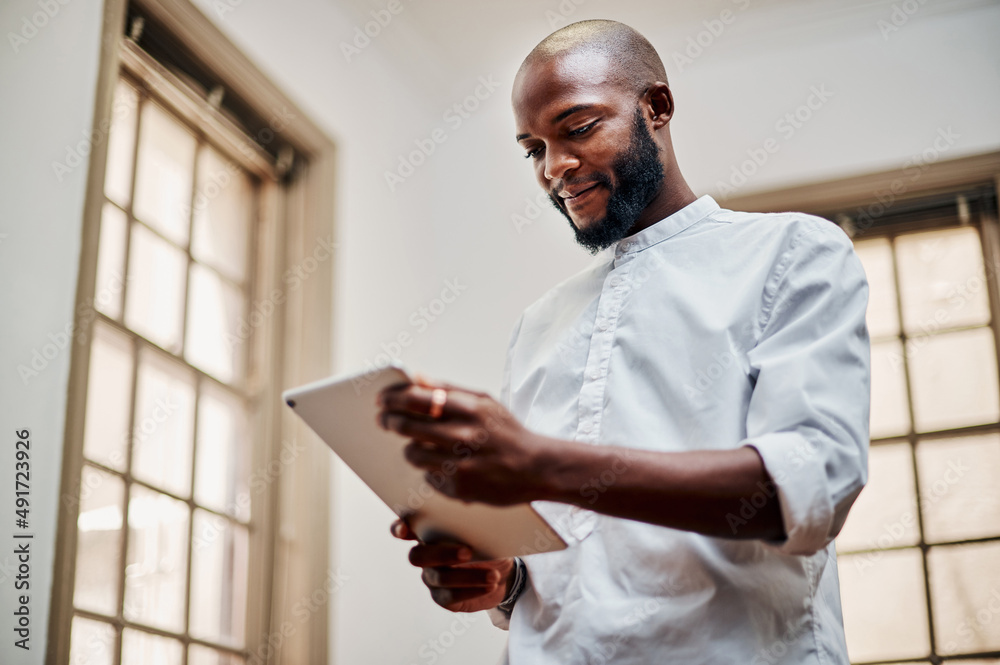 Poster a great device for a designer like him. shot of a young businessman using a digital tablet in a mode
