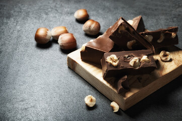 Gianduia nougat with chocolate and hazelnuts on dark gray background, space for text.