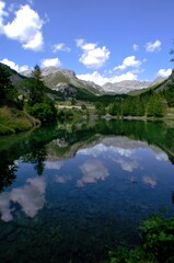 Fototapeta na wymiar Lac calme en fin d'après-midi reflétant la forêt, la montagne et le ciel peu nuageux