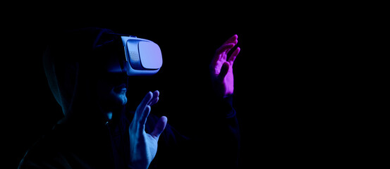 Vr glasses virtual reality. Young man in digital headset for virtual reality technology isolated on dark neon background. Amazing technology, online game, entertainment.