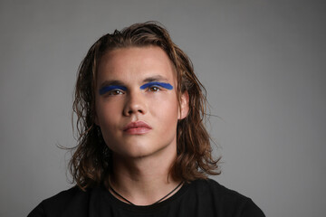 Headshot of a young man with make up and long hair posing studio. Isolated.