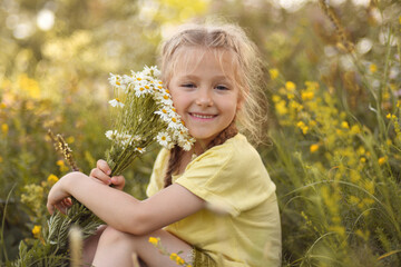 Girl with a bouquet of daisies sits in the forest