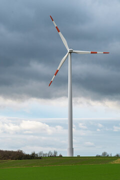 Wind turbine against a cloudy sky in a green agricultural landscape, a symbolic image for renewable and sustainable energy production