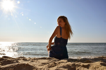 Fototapeta na wymiar Young beautiful Caucasian woman sitting on the beach by the sea looking back