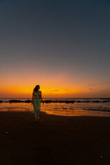 Fototapeta na wymiar woman walking on the beach at sunset on the sand enjoying the landscape