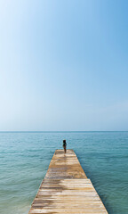 Fototapeta premium woman walking on the beach on the pier in the sand enjoying the sun and sand