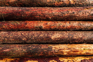 Horizontal timber log pile background texture, consisting of coniferous tree trunks with brown to red colour, Germany
