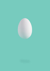 Minimal Easter composition with levitating white egg against pastel blue background.