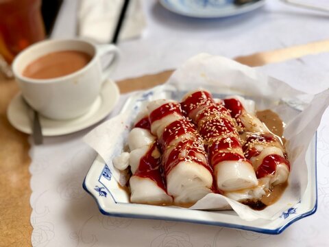 Cheung Fun (Rice Noodle) on a plate with a cup of Hong Kong Milk Tea at a Hong Kong Cafe