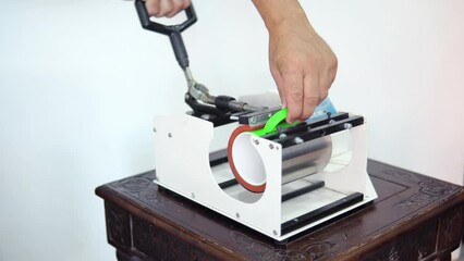 Man putting mug in thermopress for transfering an image, logo or text on the mug. Souvenirs manufacture concept