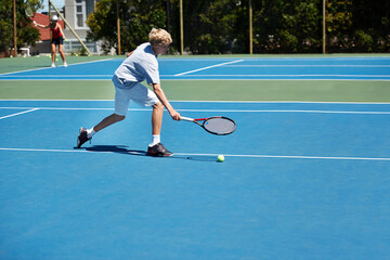 Hell be a start one day. Shot of a young boy playing tennis on a sunny day.