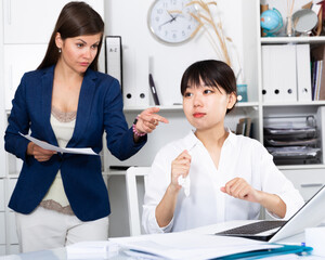 Angry boss criticizing sad frustrated female asian employee at work