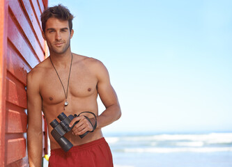 Hes looking out for danger in the water. A handsome young lifeguard at the beach.