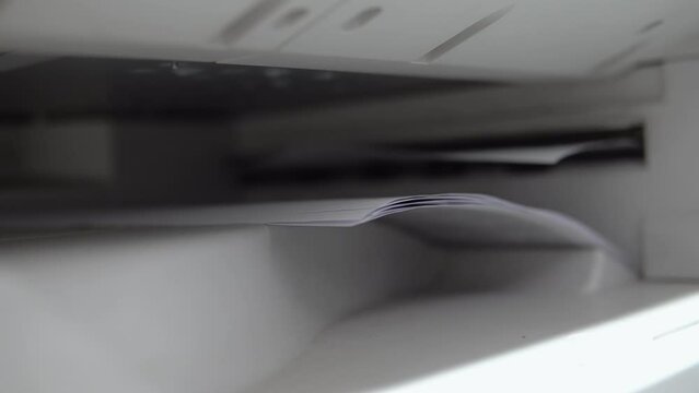 Closeup of printer, photocopier print or copy documents, sheets of paper on the laser MFP printer. Printing process in a storehouse or office