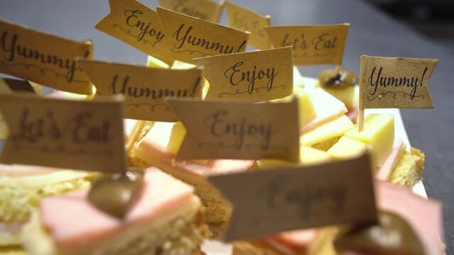 Closeup of "enjoy and yummy" flags on (mini) finger sandwiches, cancapes  on a birthday party celebration. Catering and fancy party concept