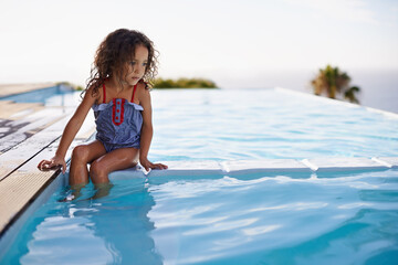 Splish Splash. Shot of a little girl dipping her feet in the pool.
