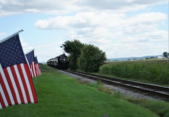 American flags flying a long a railroad with a train 