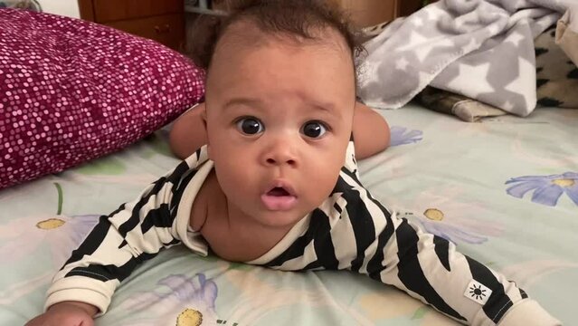 5 month lovely afroeuropean baby with big black eyes wearing a black and white body