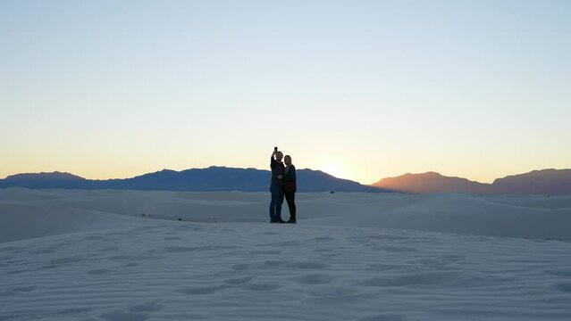 A couple taking a photo in the white sands national park during sunset