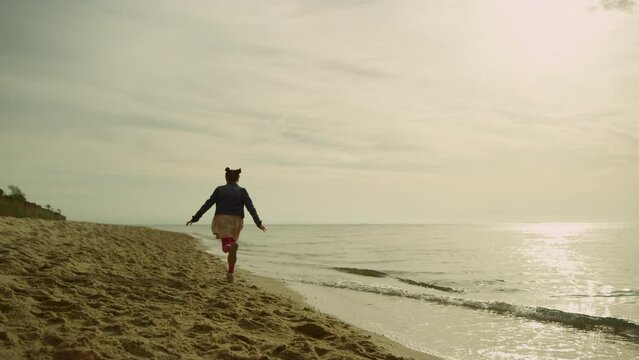 Girl running sand sea at sunset. Little child explore empty beach on sunny day.