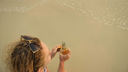 View top woman in swimwear on the beach drinks alcohol. Parting love, divorce from husband, bad...