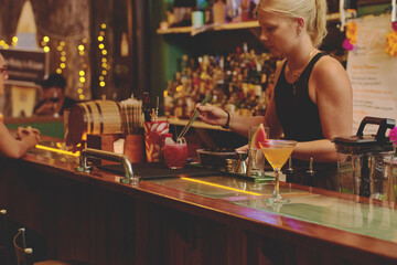 Female barman preparing drinks. cocktail bar Drinks at the bar. Fresh and cold drinks in a bar. Watermelon drink, jamiaca drink, margarita, micheladas.