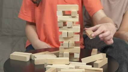 Game with wooden tower. A child play with wooden blocks. A concept of tall blocks tower on the table.