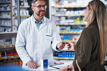 Yes, we do accept cards here. Shot of a young woman paying for merchandise with a credit card at a pharmacy.