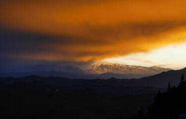 Rosso tramonto sulle cime dei monti tra luce e tenebre