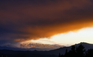 Rosso tramonto sulle cime dei monti tra luce e tenebre