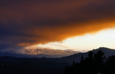 Rosso tramonto sulle cime dei monti tra luce e tenebre