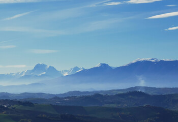 Fototapeta na wymiar Montagne innevate e vallate nel cielo azzurro in una tersa giornata di sole invernale
