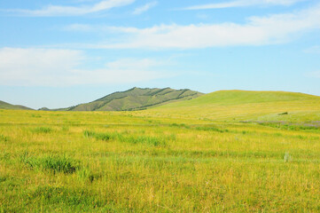 Obraz premium A mountain range on the edge of the endless steppe under a summer sunny sky.