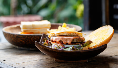 Closeup shot of delicious tasty yummy homemade breakfast juicy patty grilled beef cheeseburger with sliced vegetable lettuce cabbage tomato onion and melting spicy sauce in wooden bowl on wood table