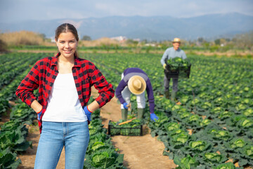 Portrait of cheerful young professional female farmer posing on a farm field