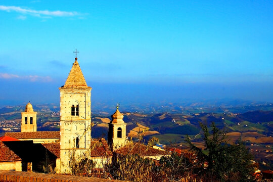 Upper part of an Italian catholic church with beautiful hilly landscape in the background under the blue sky in Penna San Giovanni