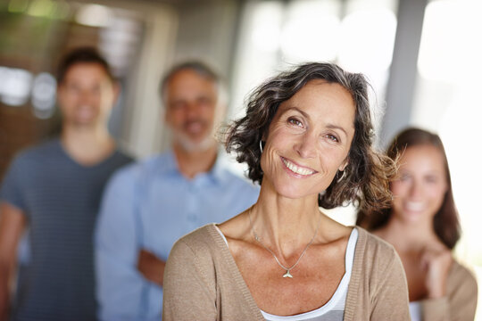 Shes the head of this house. Portrait of a happy mother with family standing behind her.