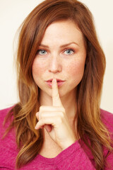 Fototapeta premium Ssh..you didnt hear it from me. Portrait of a beautiful young woman with her finger to her lips.