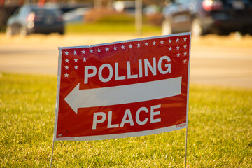 Election polling place yard sign with white text and red background.