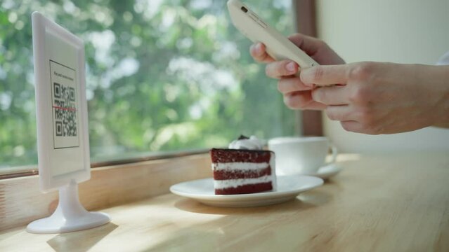 Women use phone to scan qr code to pay for coffee and cake on cafe and collect point. Mobile scanning system online for pay money.using a phone to transfer money or paying money online without cash...